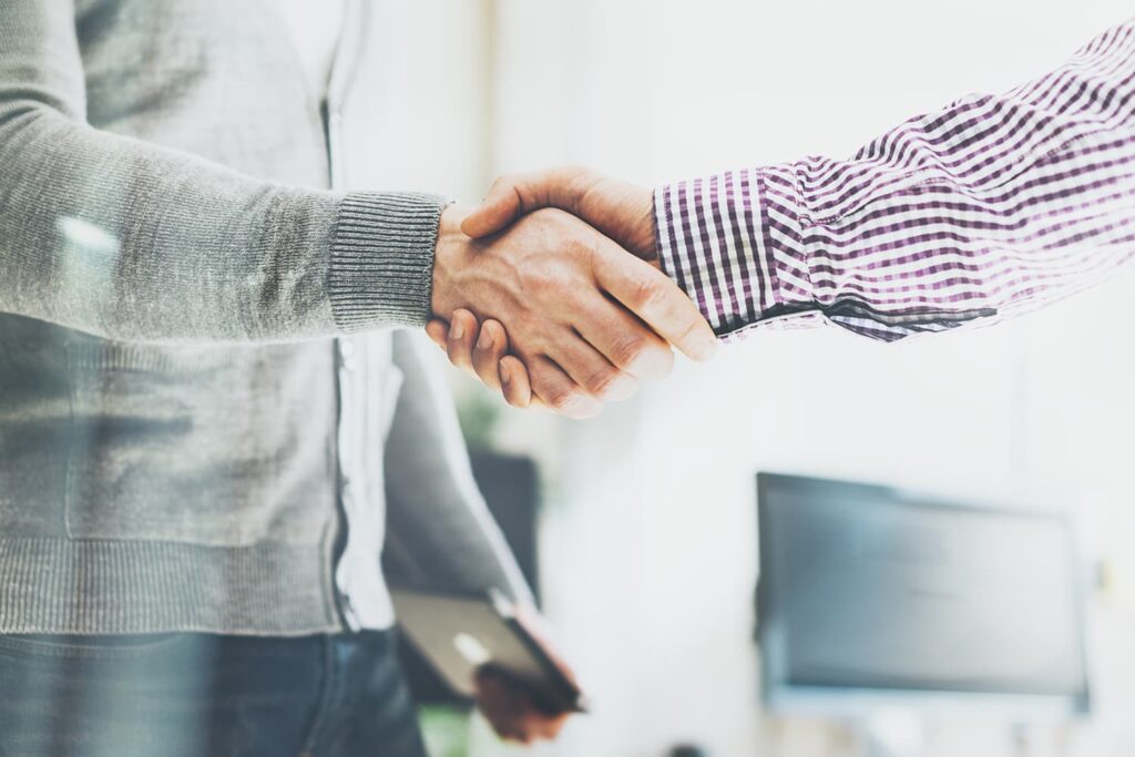 Two people shaking hands upon completion of a successful business acquisition with Commonwealth M&A